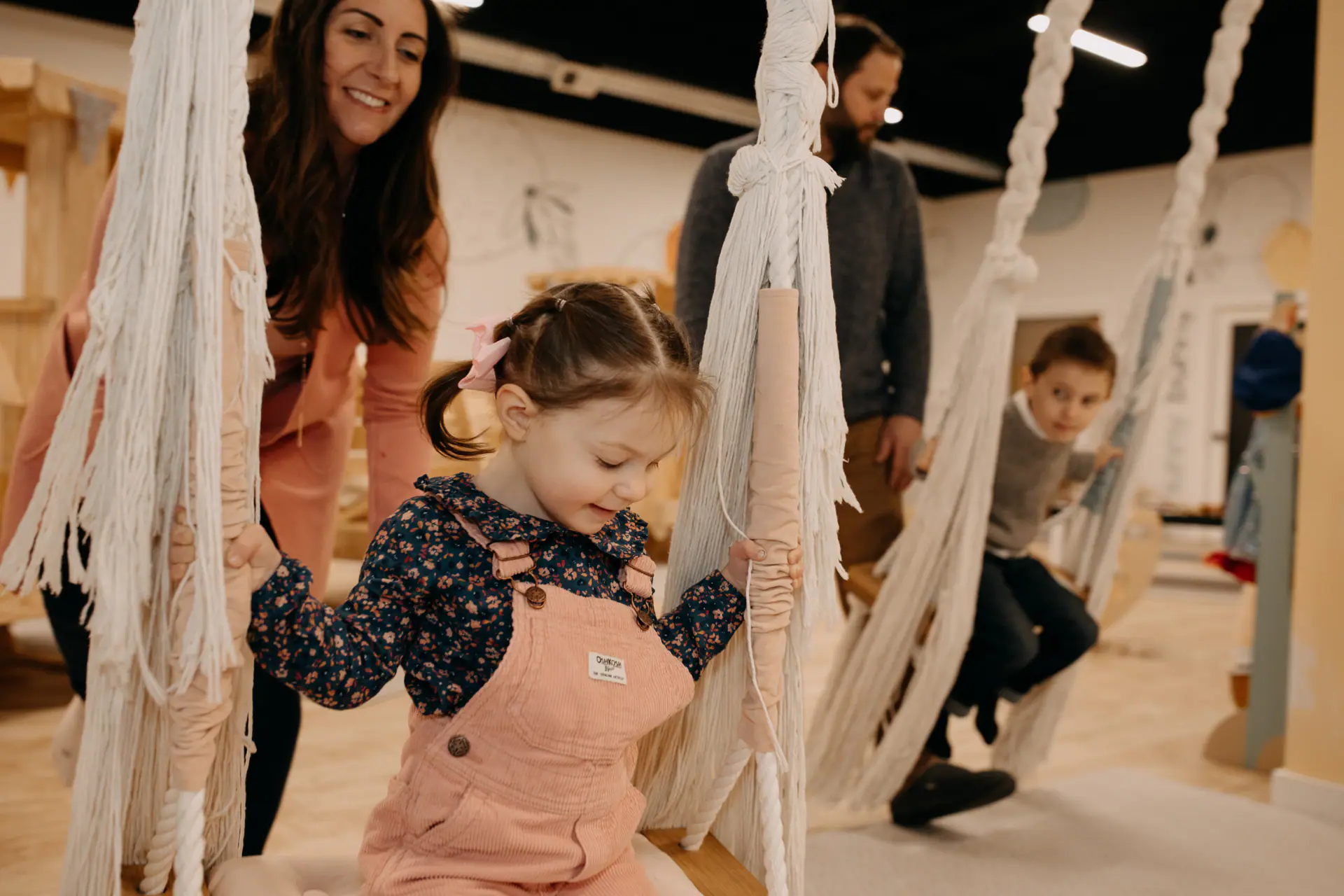 Child using a fabric swing feature at The Little Things Play Cafe.