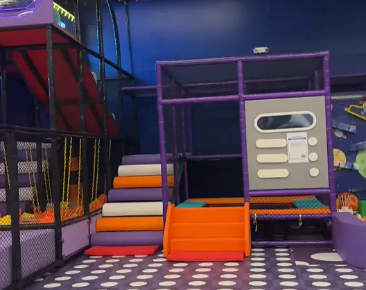 Lower-profile soft-play section with steps and a short slide at Kids Jungle Playground