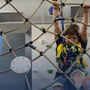 Child navigating a rope climbing feature at Play Climb.