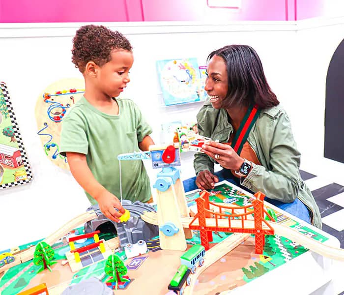 Caregiver and child playing at a train table inside Electric Donuts Play Cafe.