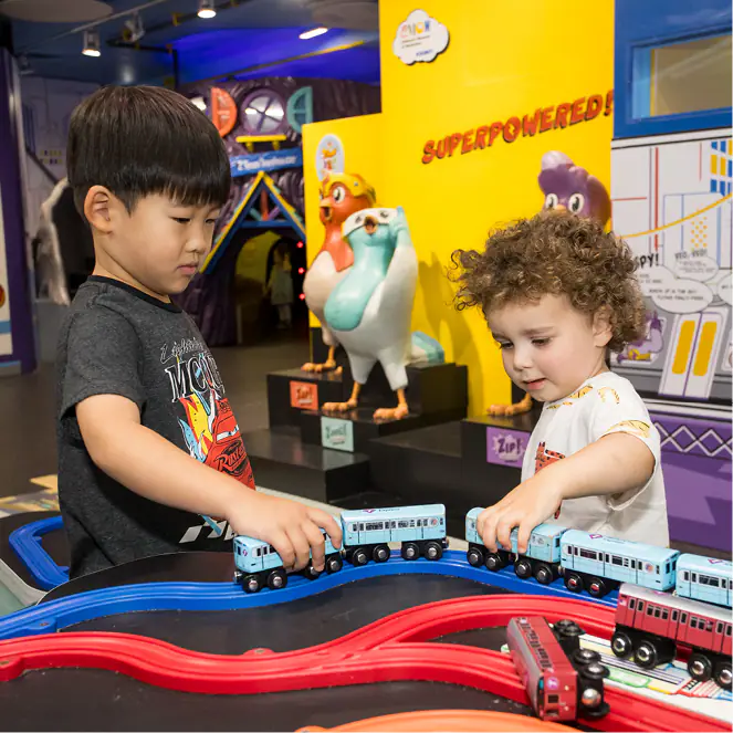 Children playing at a train table exhibit inside the Children's Museum of Manhattan.