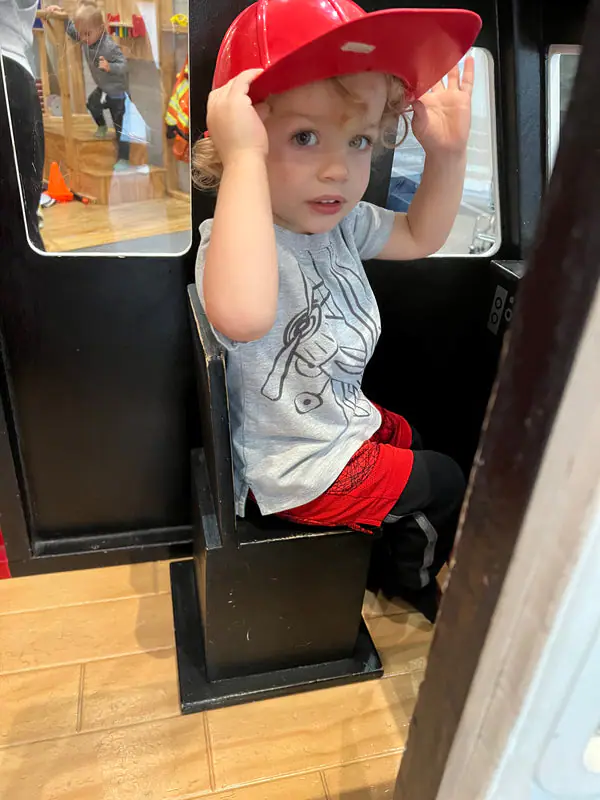 Child sitting inside a pretend-play fire truck at The Little Play Co.