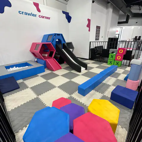 Crawler corner with low climbing pieces and a slide at Bounce N Play Pearland.