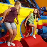 Children climbing and playing on giant inflatable equipment during a Pump It Up session.
