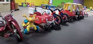 Row of ride-on toys lined up inside Children's World Indoor Playground.