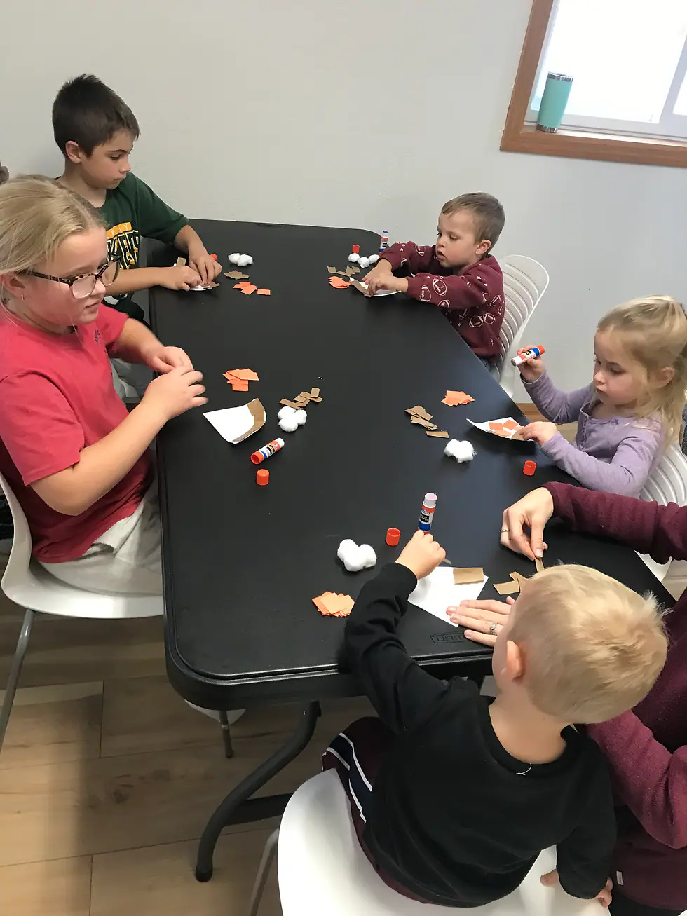 Children doing a craft activity together at a table inside Happy Hive.