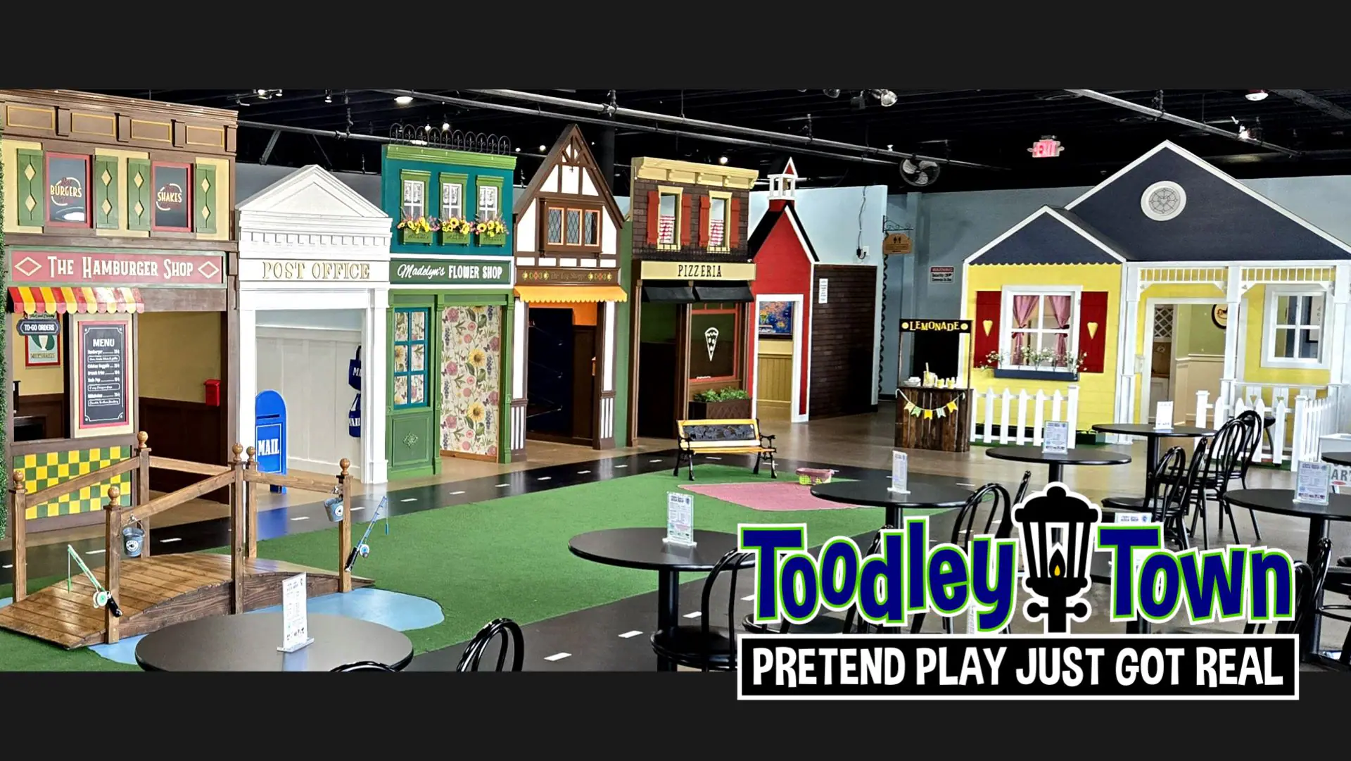 Children playing inside themed pretend-play storefronts and home-style spaces.