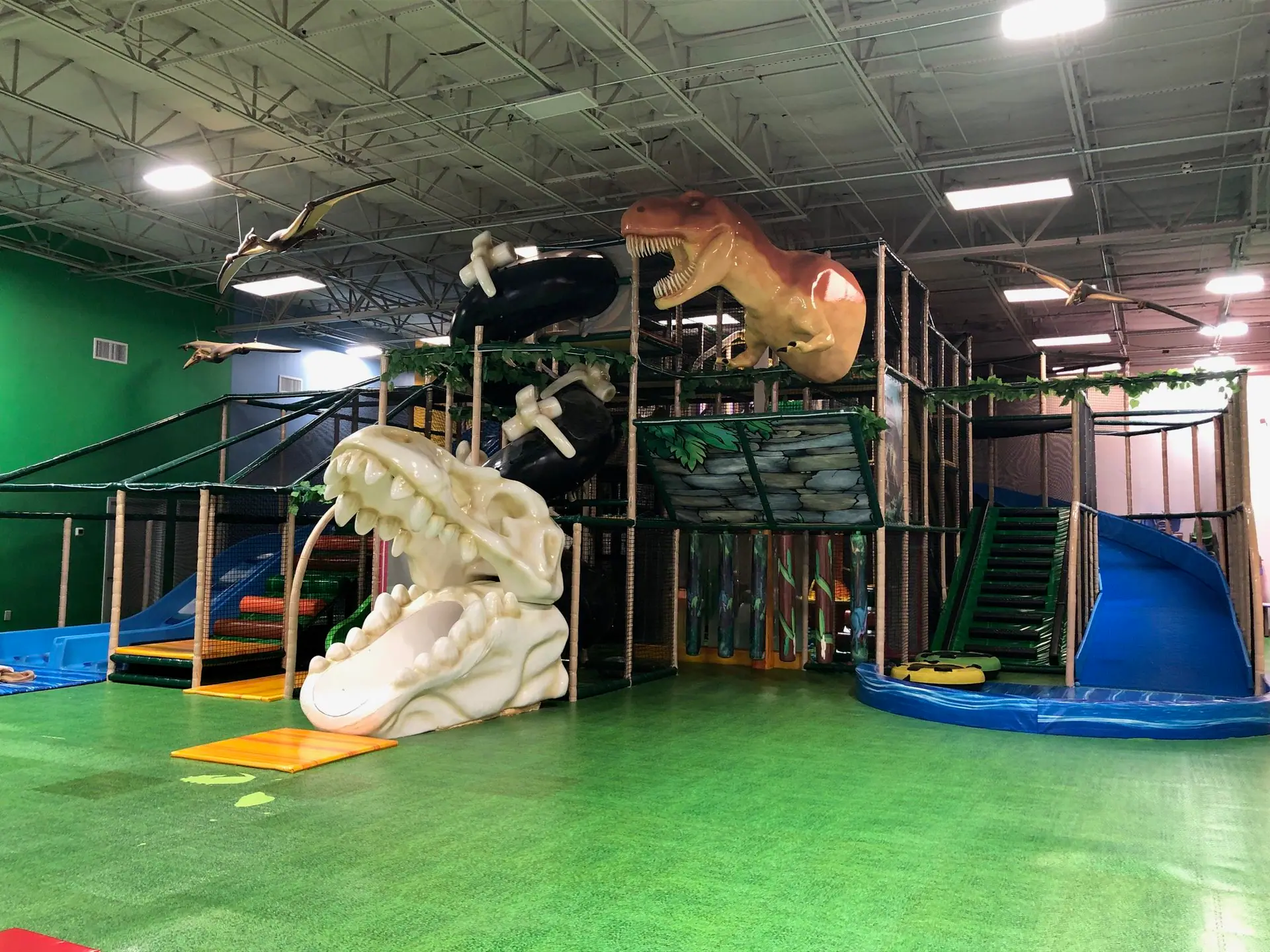 Dinosaur-themed climbing structure inside Happy Land Indoor Playground in Jackson