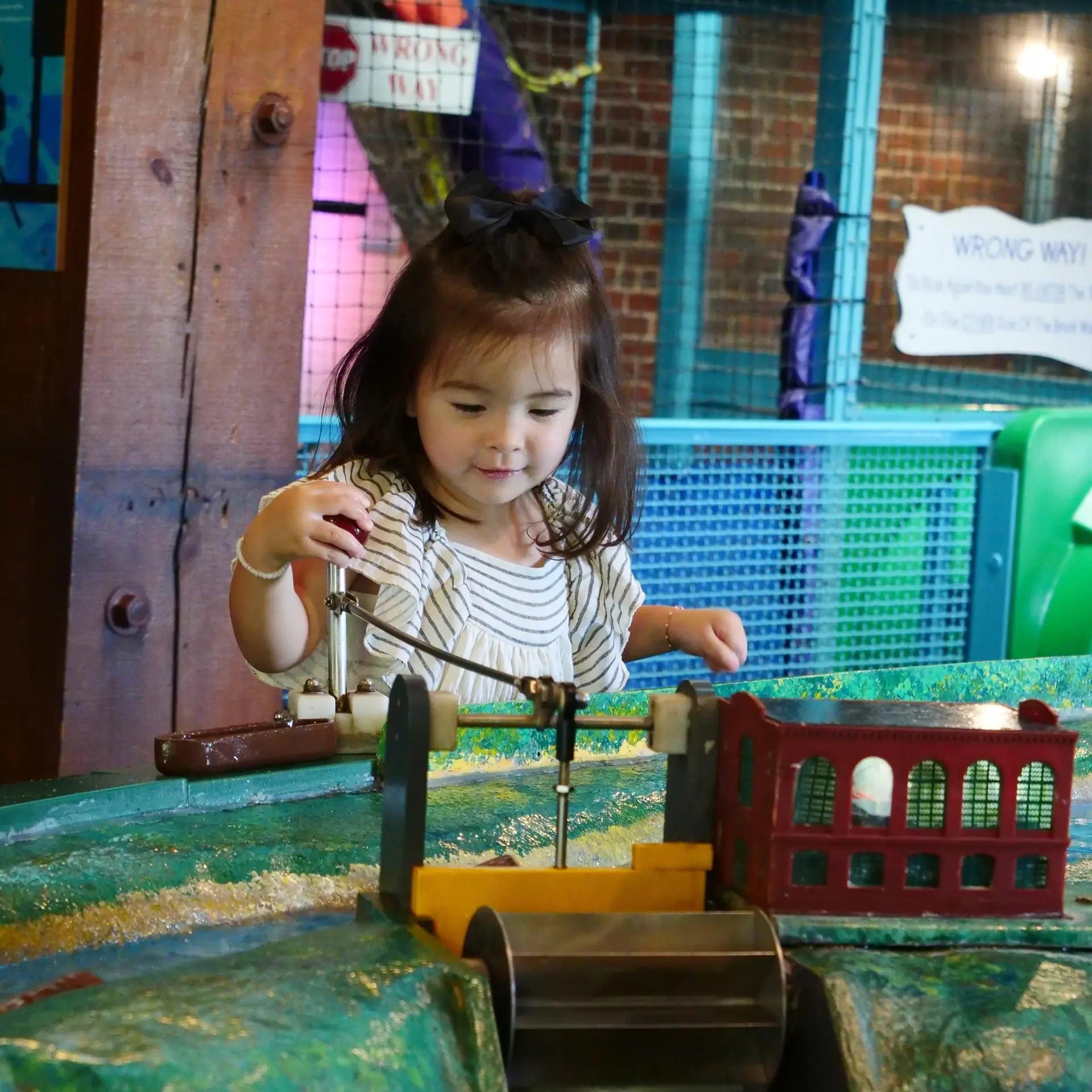 Young child playing at a hands-on water and discovery exhibit inside Amazement Square.