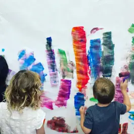 Children painting on a large shared wall at Redwood Discovery Museum