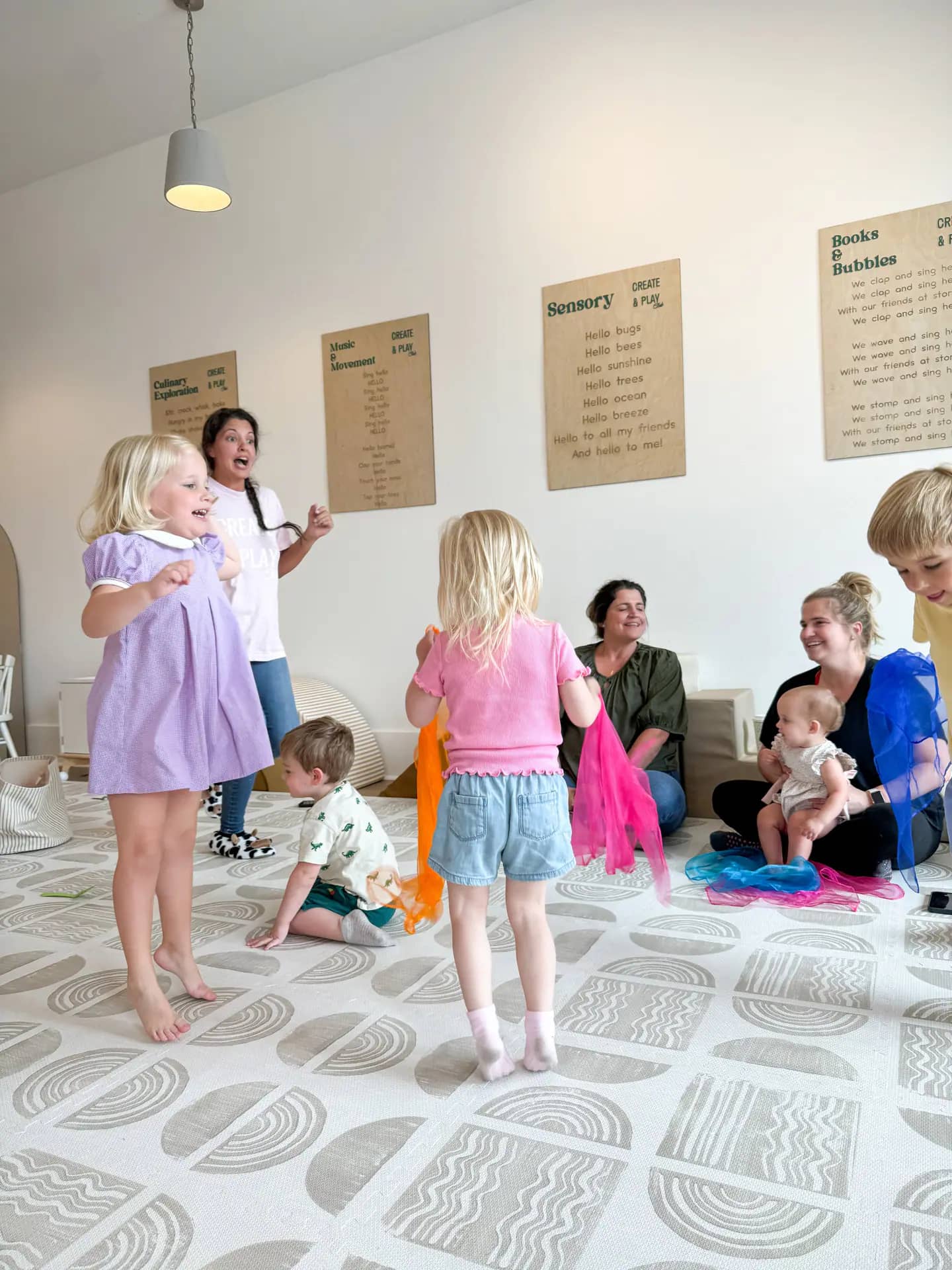 Caregiver-and-child music or movement class on a soft play floor.