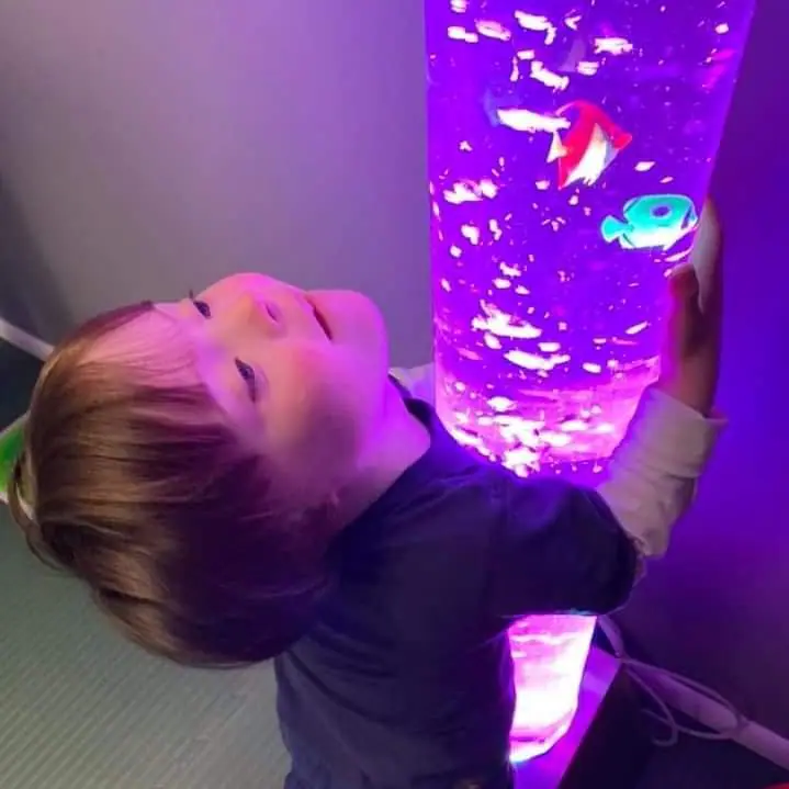 Young child looking at a glowing sensory bubble tube.