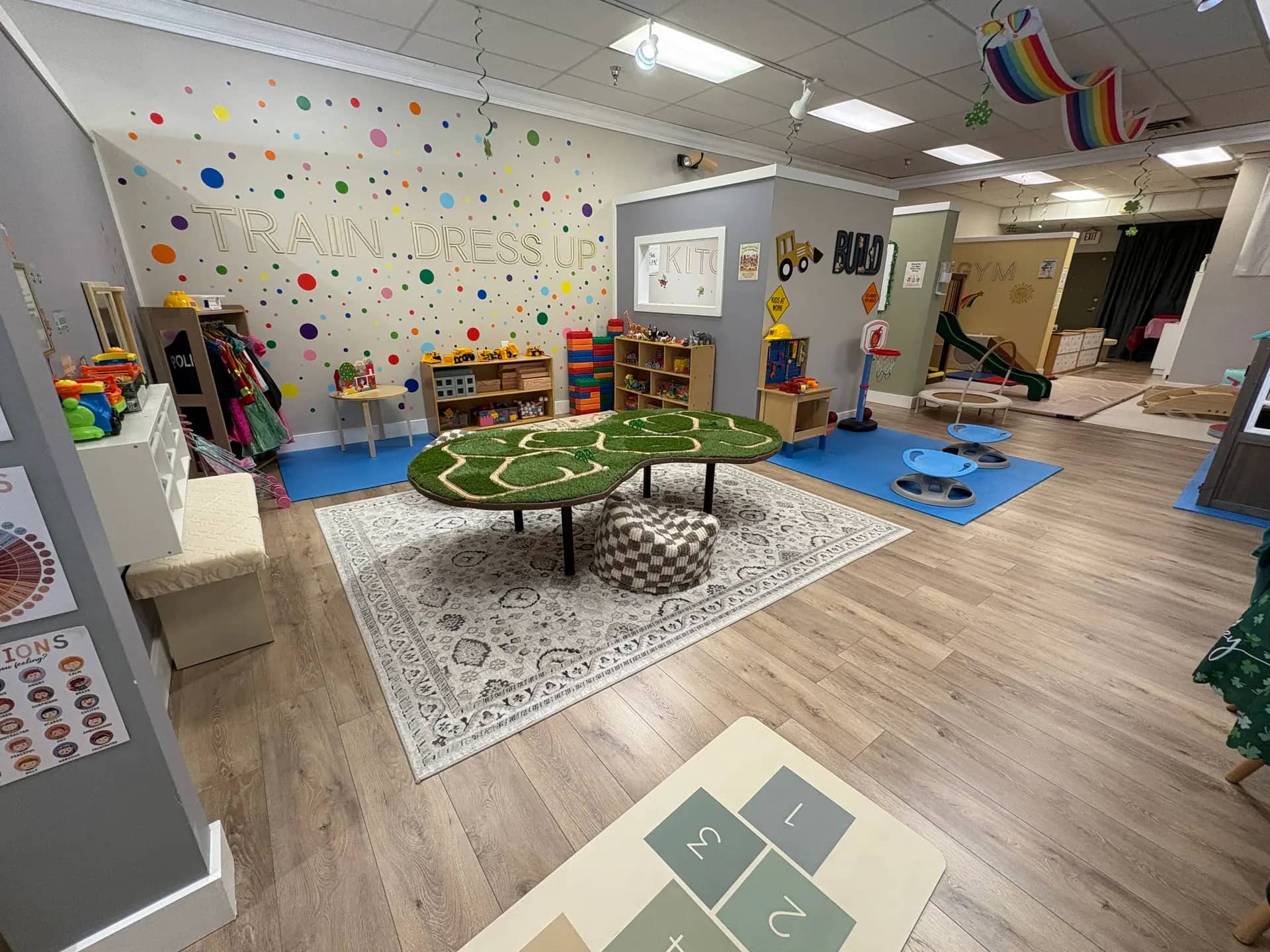 Train and dress-up station at Kidscape Playground with costumes, toys, and open play space.