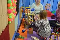 Children using sensory and motor-play materials inside Imagination Station.