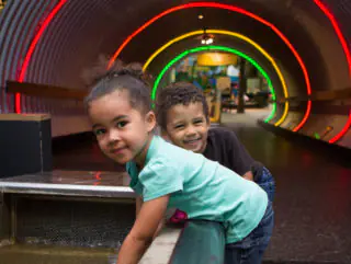 Children moving through a colorful tunnel exhibit at Brooklyn Children's Museum.