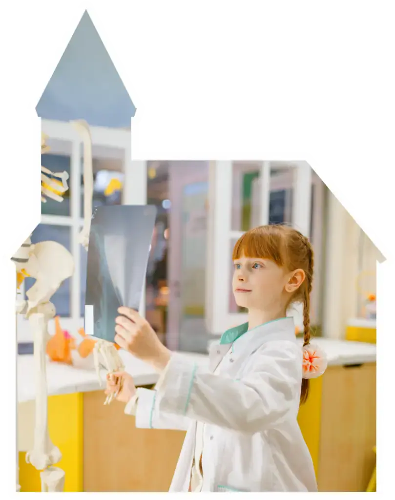 Child holding an x-ray in a pretend clinic area at Curiosity Avenue.