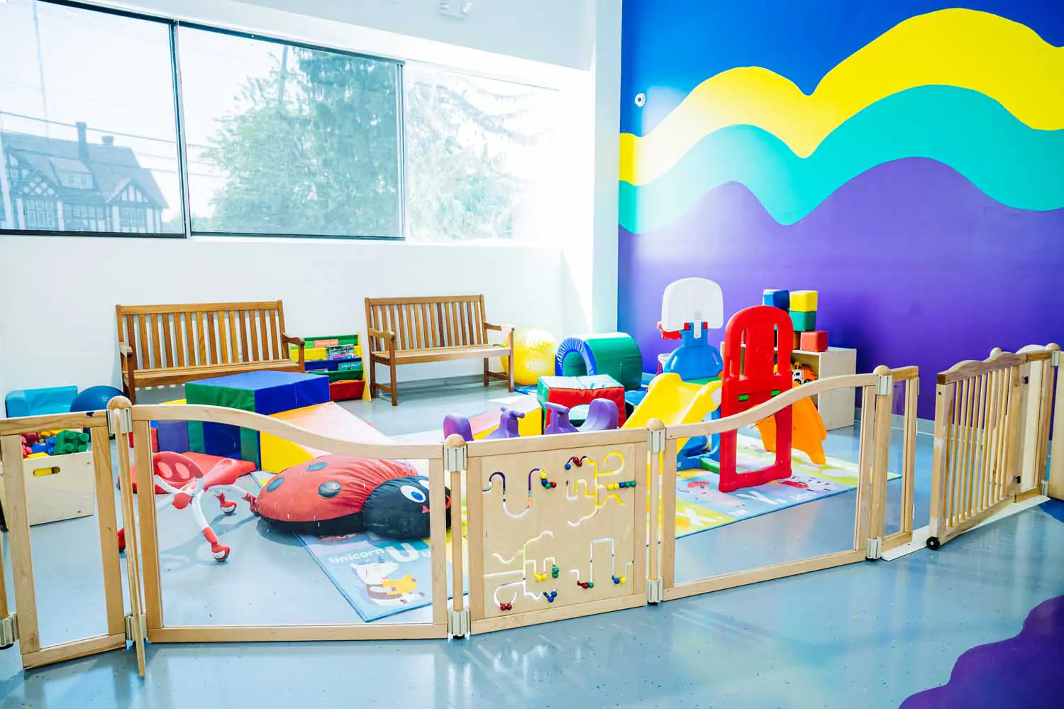 Toddler play zone at Kids At Play with fenced soft-play equipment and small slide.