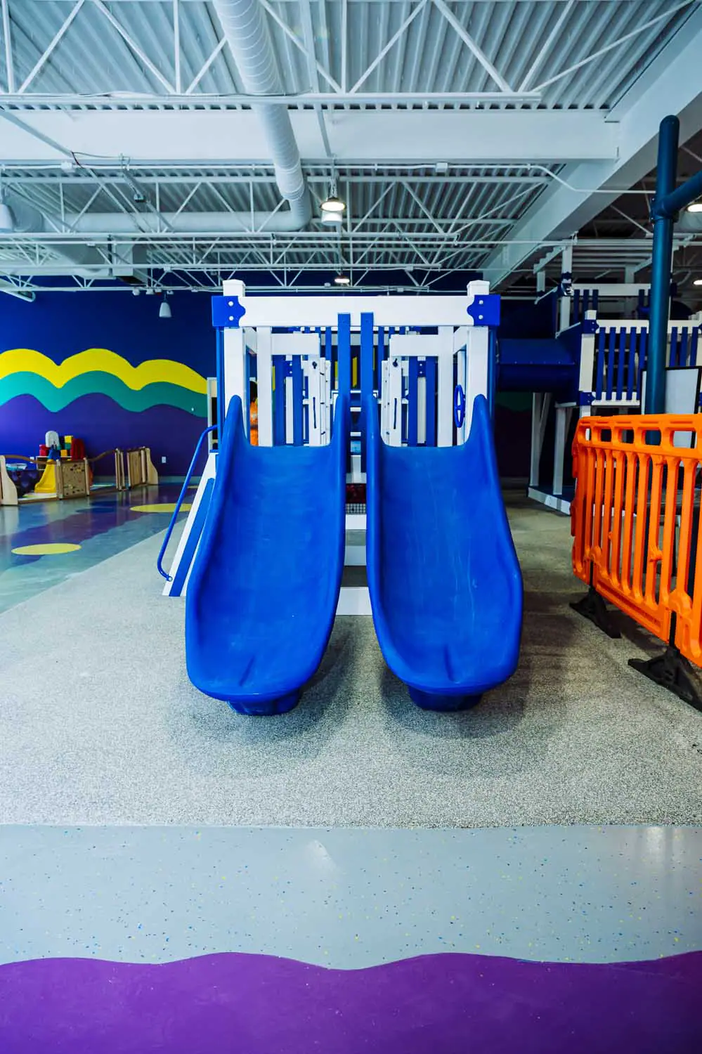 Blue slide structure inside the Kids At Play sensory playground.