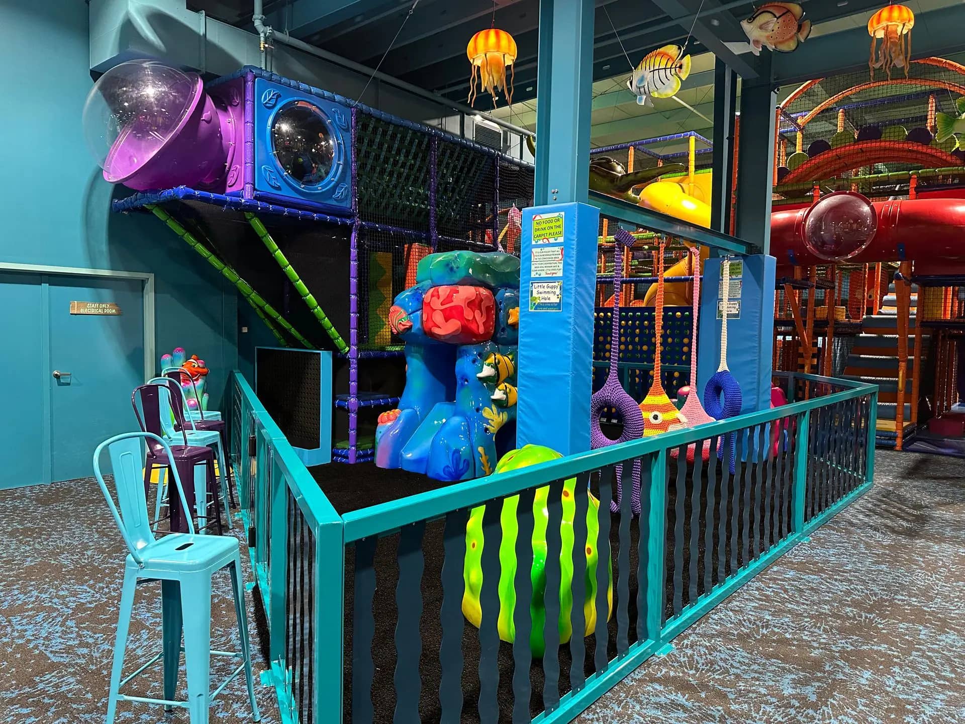 Toddler play area with small structure, swings, and sea-themed decor at Deep Blue Indoor Play.