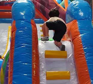 Toddler climbing obstacle inside Jumbo Park Texas Adventure.