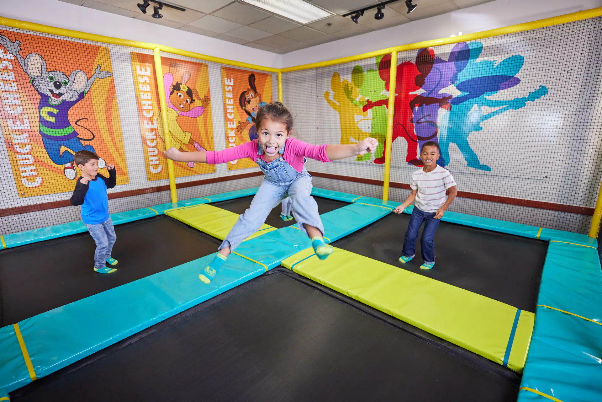 Kids jumping in a Chuck E. Cheese trampoline attraction.