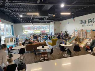 Wide view of the play café with table seating and indoor play space.