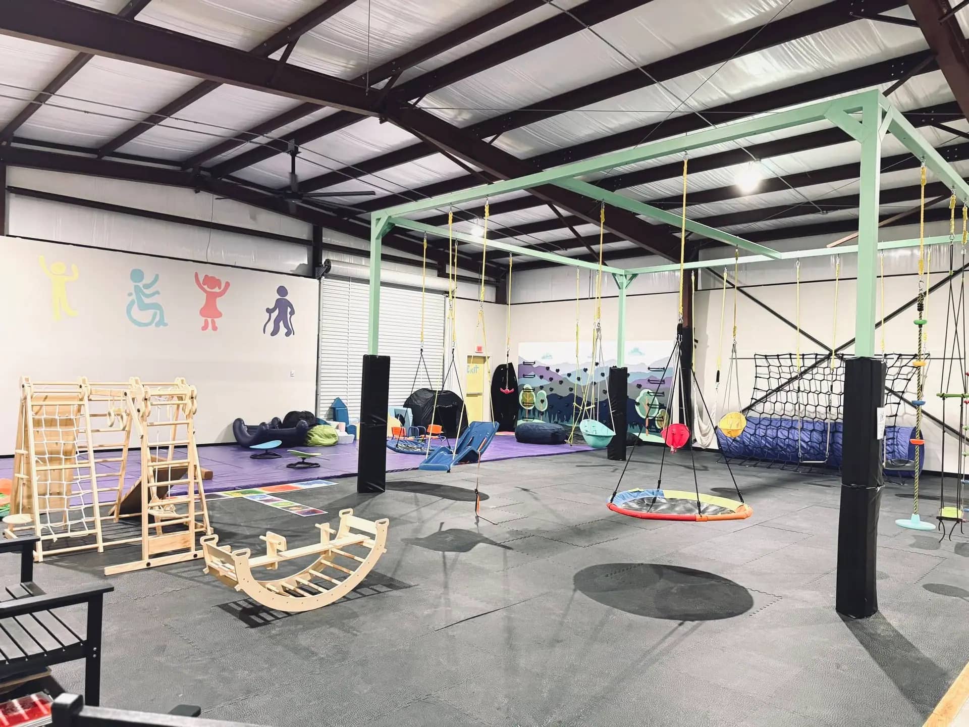 Open sensory gym floor with swings, climbing elements, and soft play space at Jake's Place in Ball.