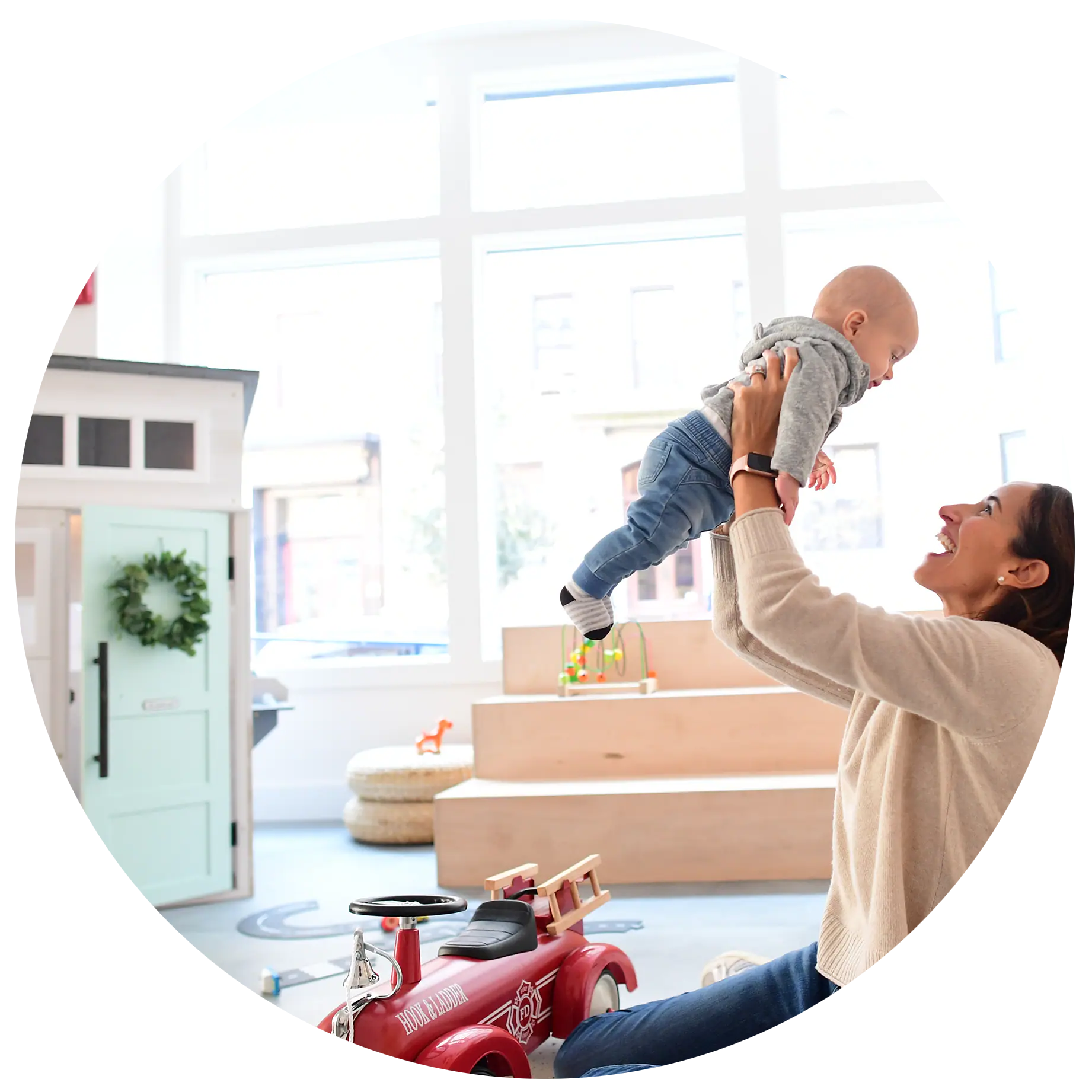 Caregiver lifting a baby in the play area at The Hive.