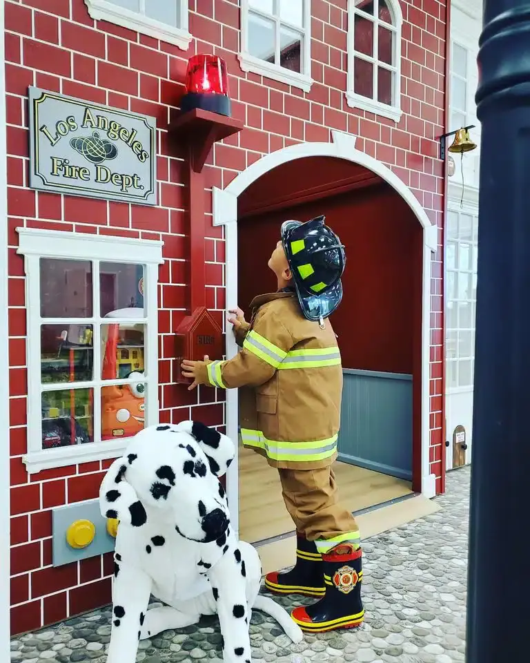 Child in firefighter gear at the pretend fire station at UDLC Play Place