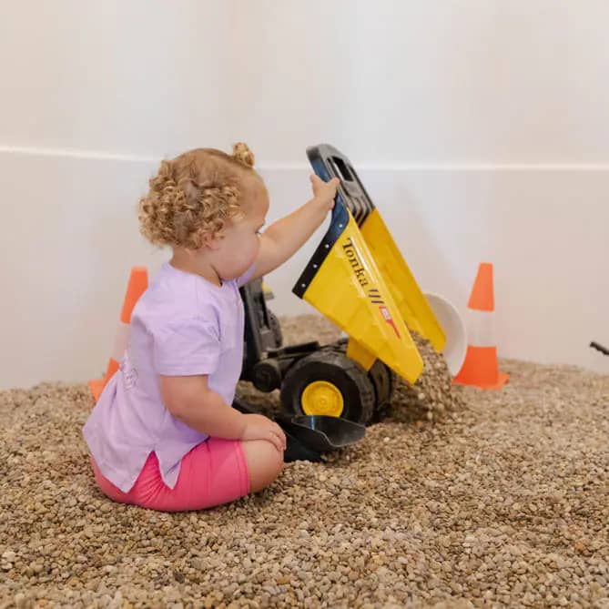 Toddler using dump-truck play station at Dorothy's Playhouse.