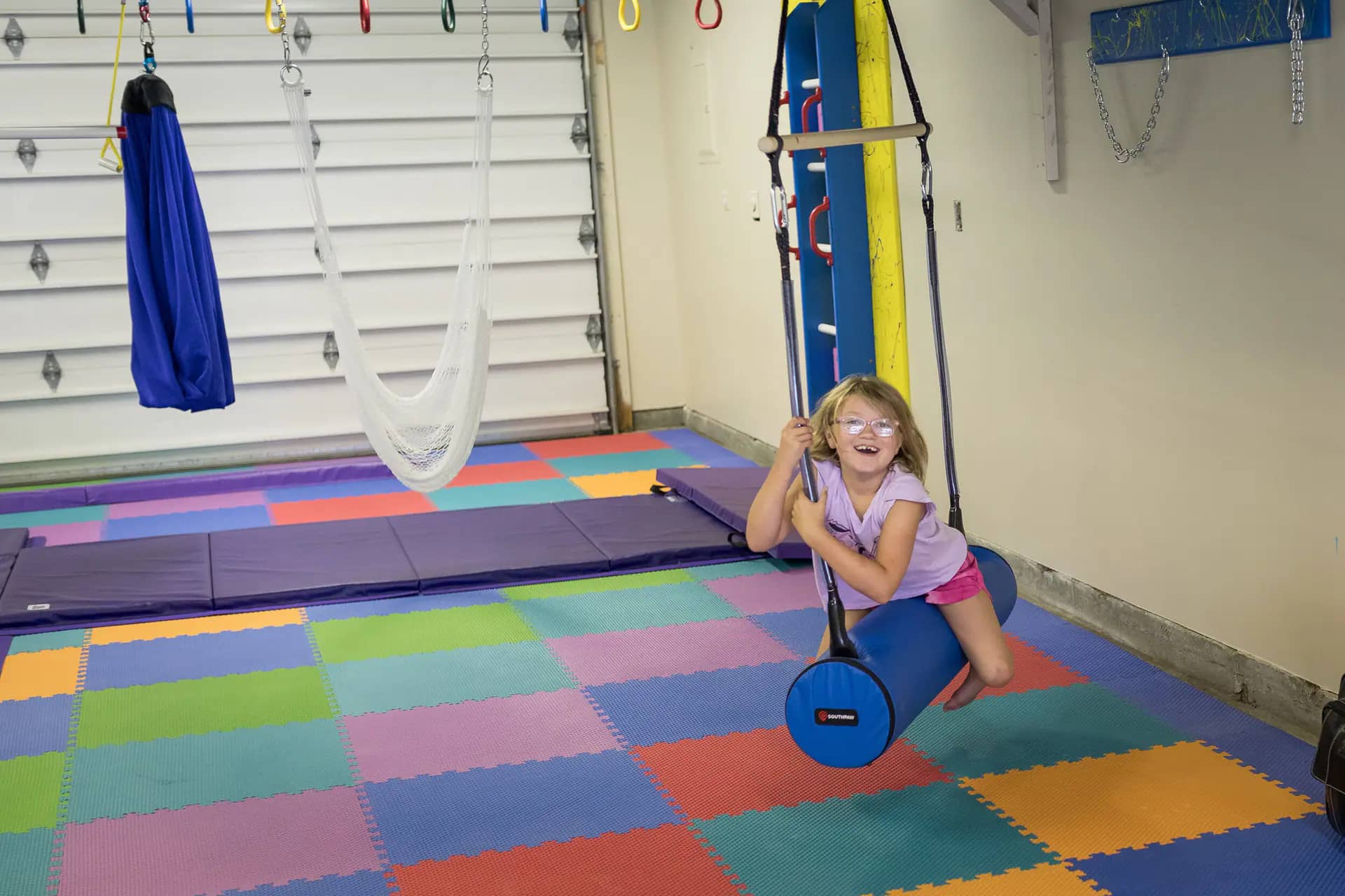 Child using sensory-friendly gym equipment inside Rylee's Play Place.