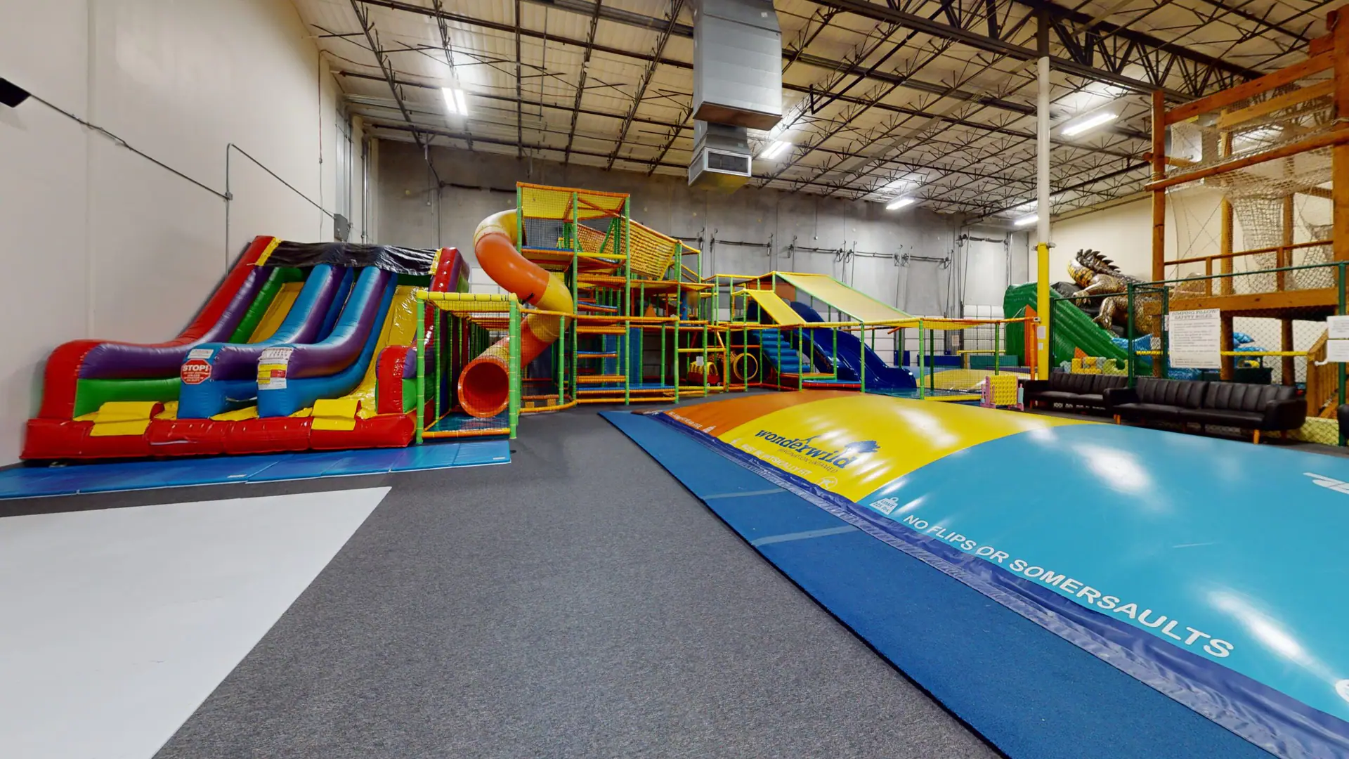 Wide view of Wonderwild's indoor playground with inflatable slides, climbing structures, and a large jumping surface.