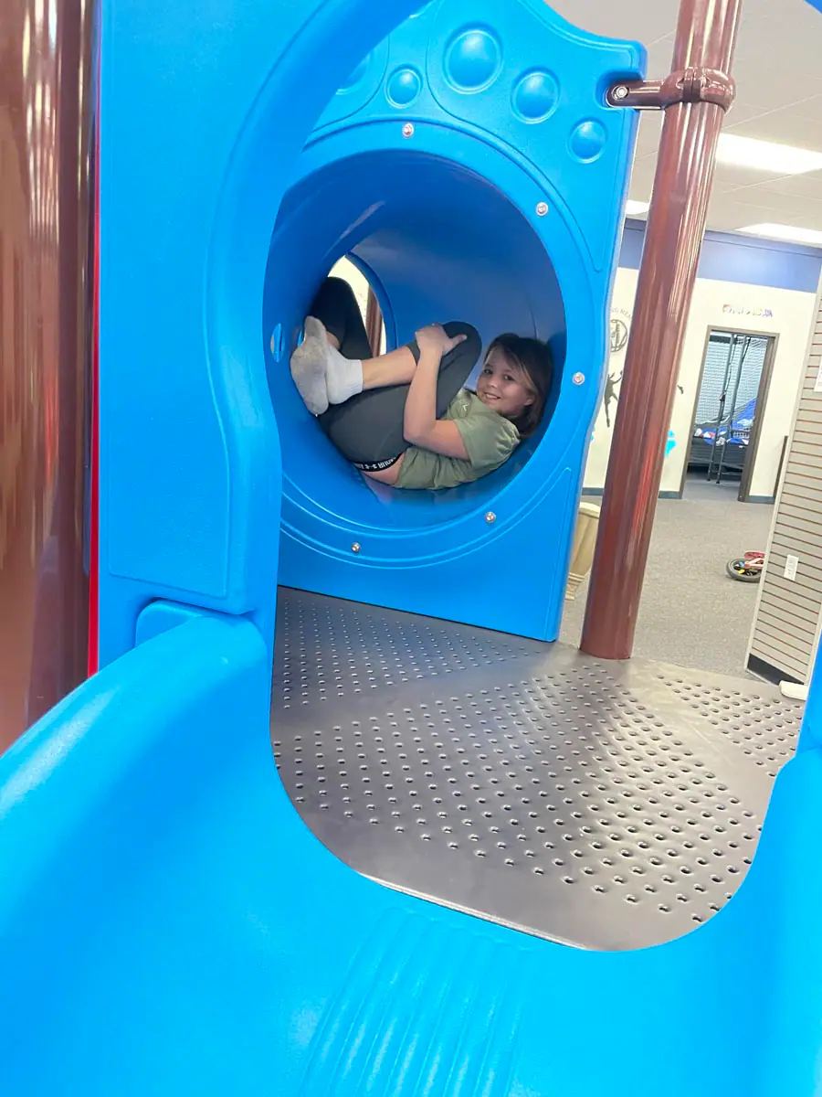 Child playing inside the blue tunnel section of the main structure at Superior Funland