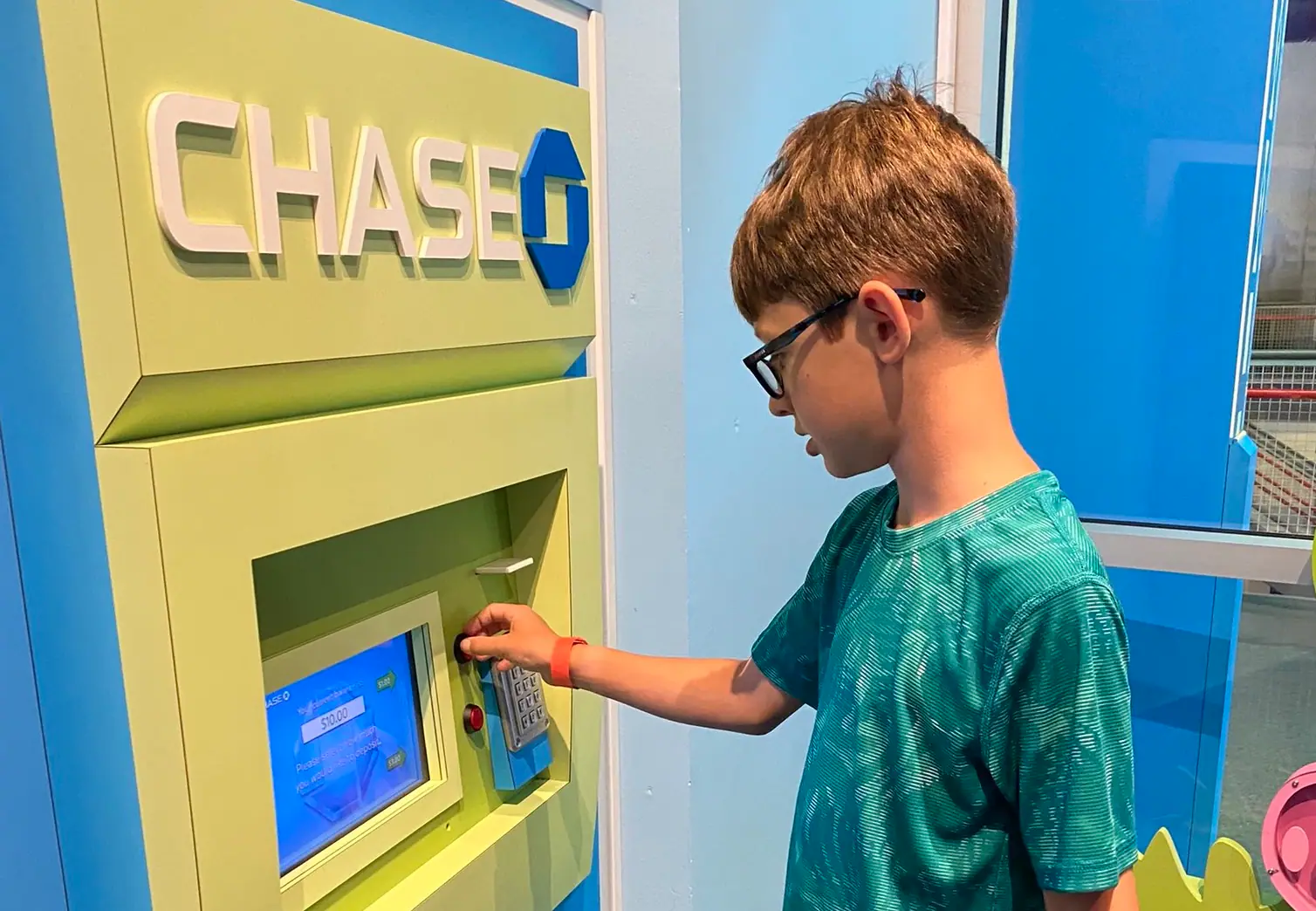 Child using the bank-style pretend-play exhibit at PoP Children’s Museum.