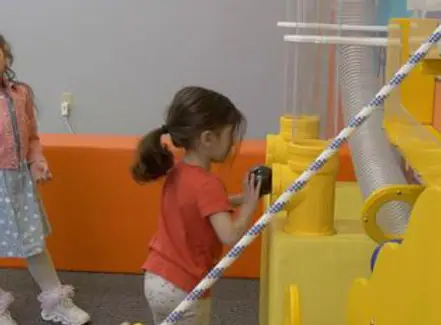 Child using the ball-wall style exhibit at Hershey Children's Museum.
