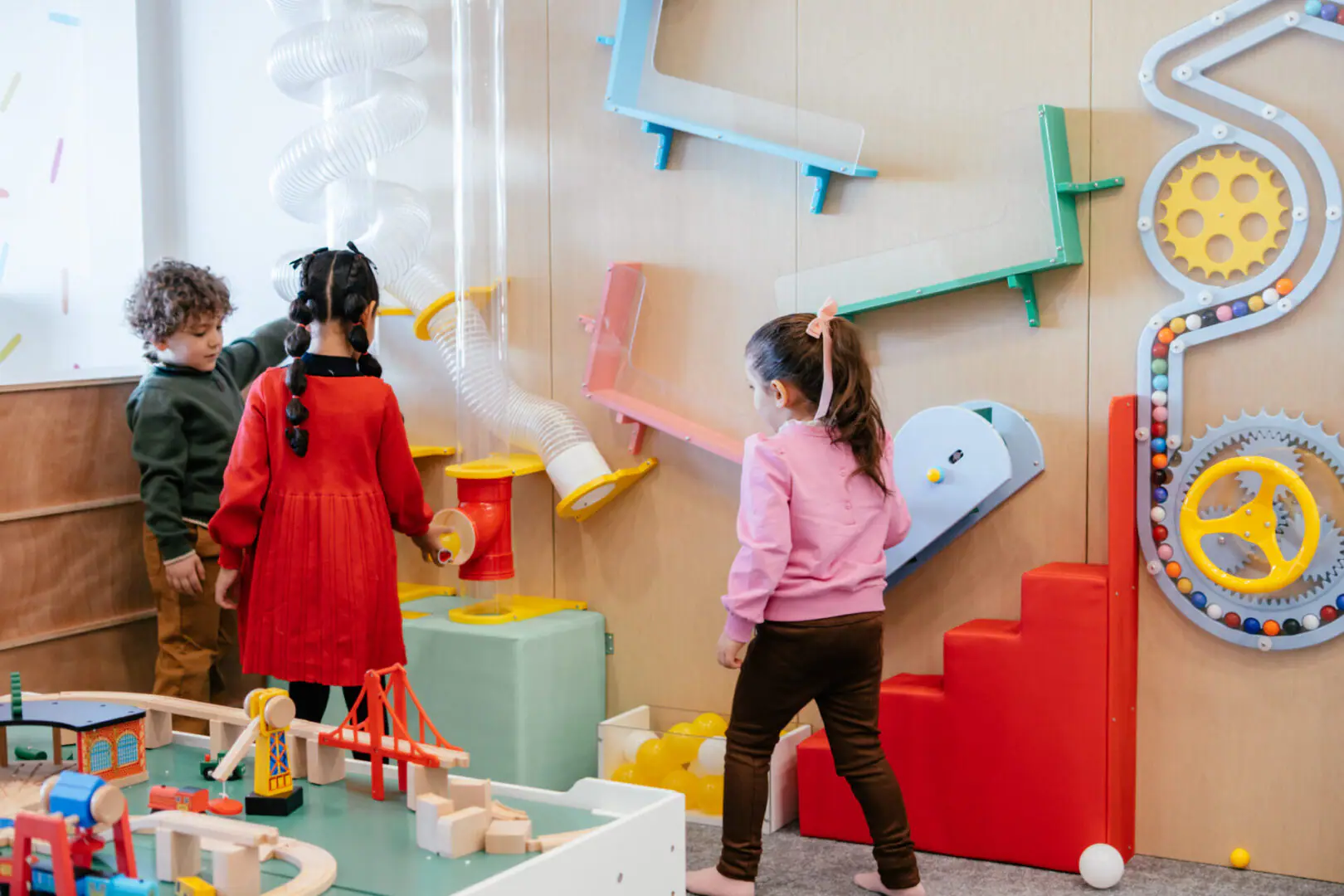 Children exploring a wall activity station at Happy Play Day.