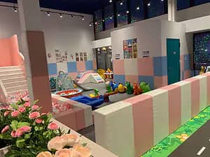 Toddler-scale play zone with ride-on toys and padded fencing at PeekabooO.