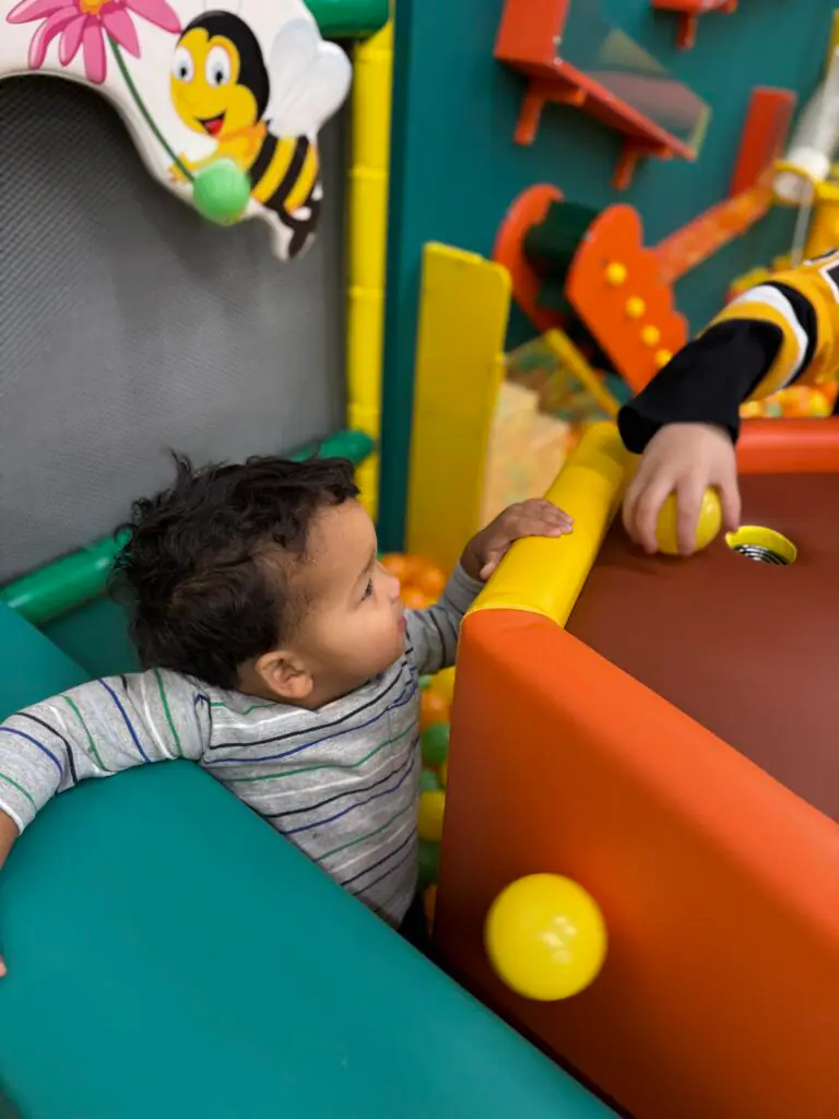 Young child playing beside the ball pit at Kids Play Hive.