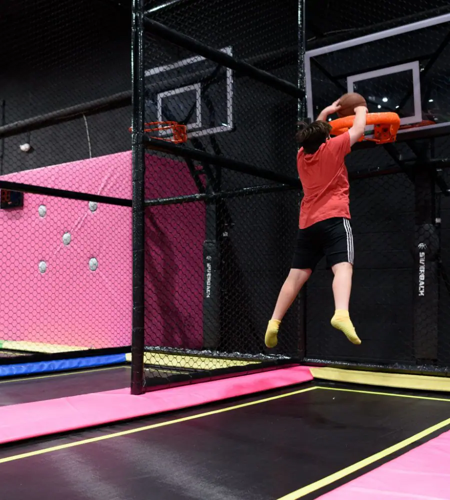 A child shooting hoops in the trampoline basketball area at Fun City Adventure Park.