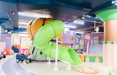 Green tube slide and pastel play structures at PeekabooO 21st Street.