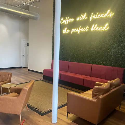 Lounge seating area with a neon sign at run+play kids cafe.