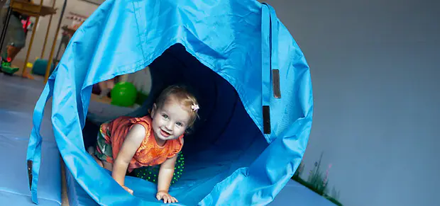 Toddler crawling through a soft tunnel at Sensory Seekers.