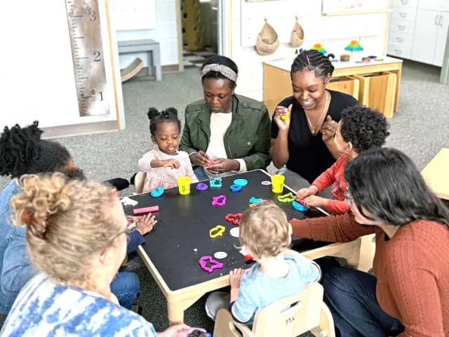 Young children and caregivers playing together inside The Nest.
