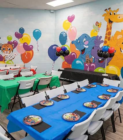 Party tables with balloons and character mural at Kidzville Catonsville.