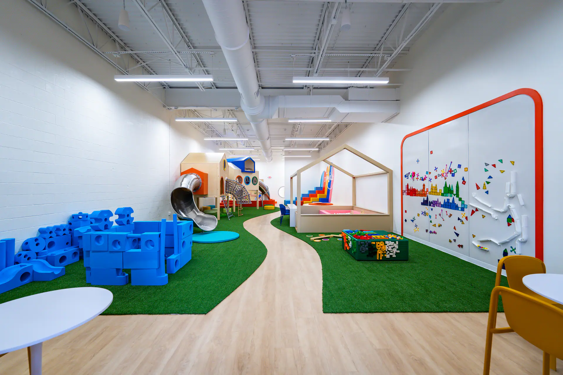 Bright indoor playroom at Playground Abode with soft-play structures, seating, and open space for young children.