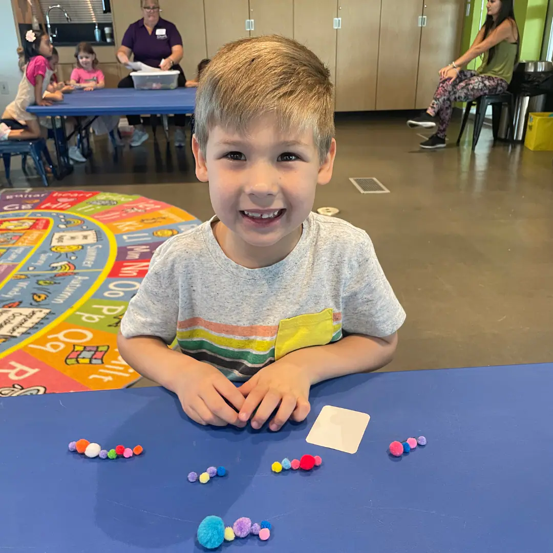 Child smiling at an activity table inside CMON.