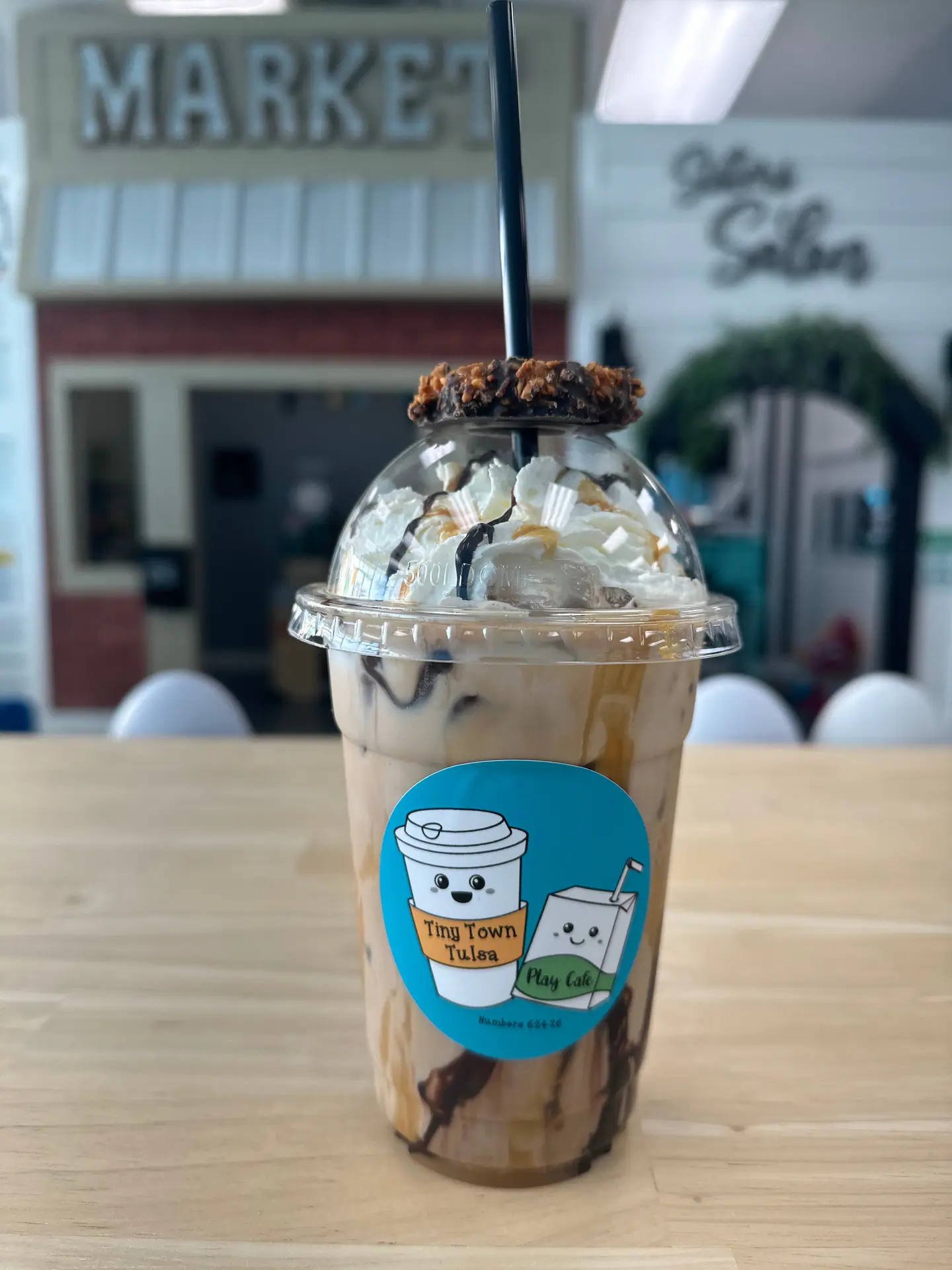 Coffee drink served inside Tulsa Play & Cafe with the play space in the background.