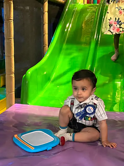 Toddler sitting at the base of a bright green slide at Funzy Play Newport.