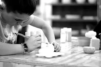 Child painting pottery at a table inside Creative Adventure Lab.