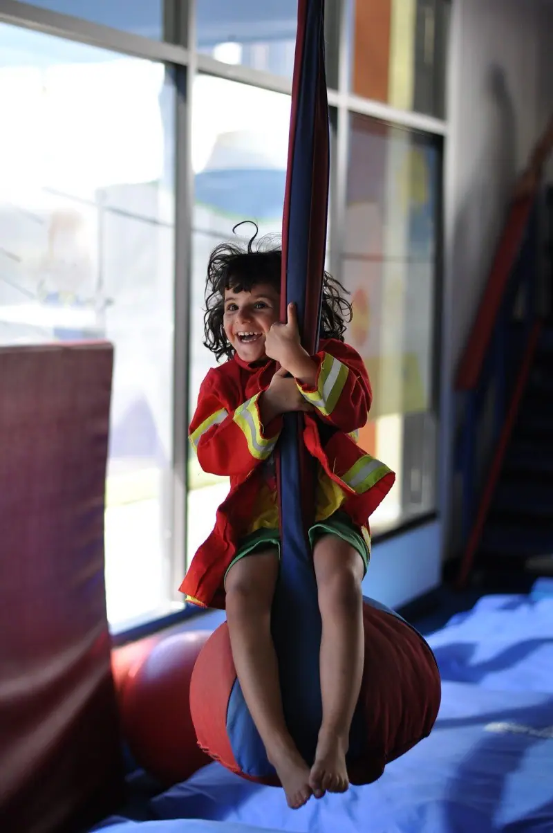 Child smiling while swinging at We Rock the Spectrum Naples